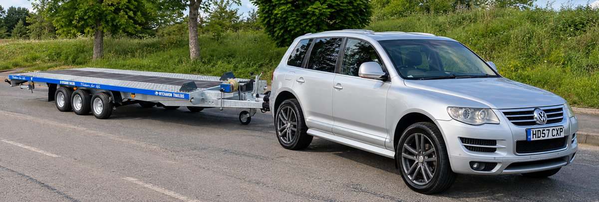 Onagone silver Volkswagen Touareg with tri-axle vehicle recovery trailer